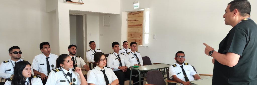 Estudiantes de aviación uniformados escuchando atentamente a un profesor en el aula, en la sección sobre por qué elegir la formación de Dream Fly.