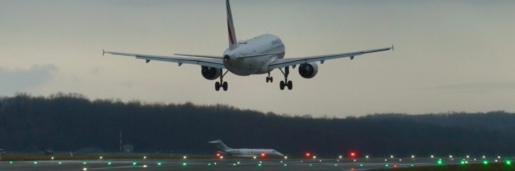 Avión de pasajeros aproximándose a la pista de aterrizaje de noche, con luces de borde de pista visibles, ilustrando el punto sobre 'Los 4 componentes del SMS: El mapa de la seguridad