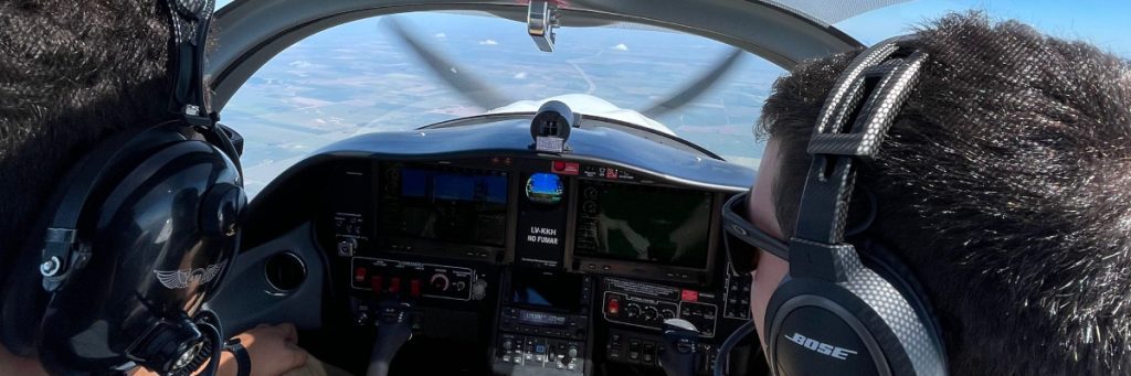 Dos pilotos con auriculares sentados en la cabina de un avión durante el vuelo, mostrando la colaboración y el trabajo en equipo en el aire.