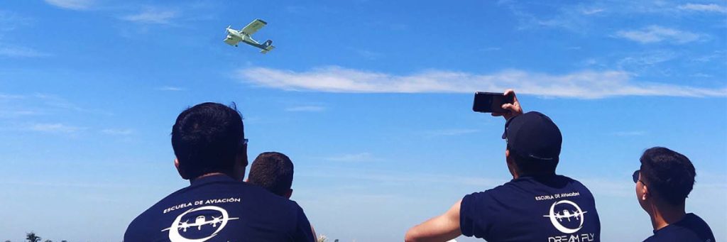 Estudiantes de aviación observando el vuelo de un avión mientras cumplen su sueño de volar.