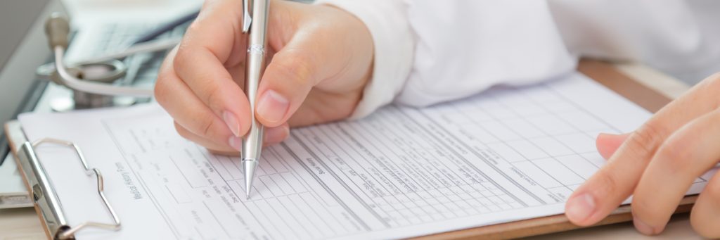 Manos de un médico examinando y llenando un formato de certificado médico aeronáutico durante la revisión médica obligatoria para pilotos en Bogotá.