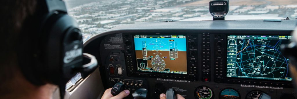 Piloto monitoreando sistemas de vuelo en cabina de cristal, ilustrando la tecnología y la demanda laboral en la aviación.