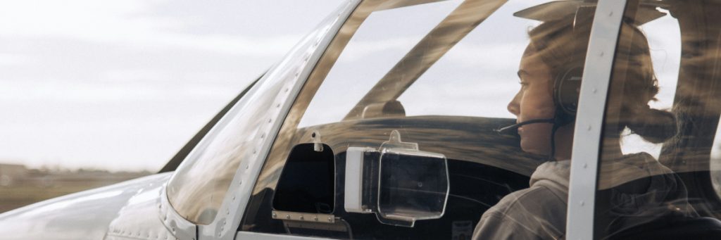 Mujer piloto sonriendo dentro de una avioneta, ilustrando las oportunidades laborales y el sueldo piloto recién egresado.
