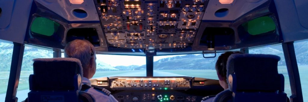 Vista desde la parte trasera de un simulador de vuelo, mostrando los paneles de control y las pantallas durante una sesión de entrenamiento.